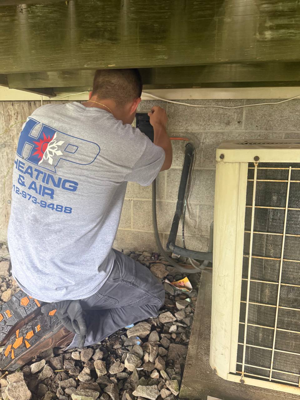 HP Heating & Air technician servicing an AC unit at a Pittsburgh home
